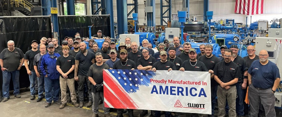 FS Elliott employees grouped together holding a Proudly Manufactured in America sign